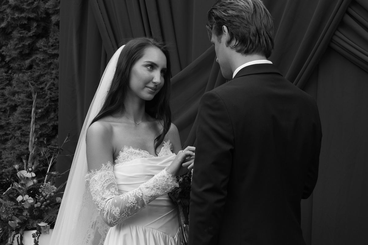 Czułe spojrzenie panny młodej podczas ceremonii pod ciemną kurtyną